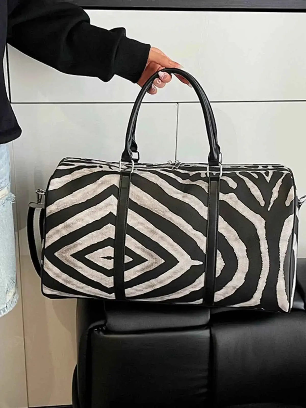 Large zebra print duffle bag in black and white PU leather with black handles and adjustable shoulder strap