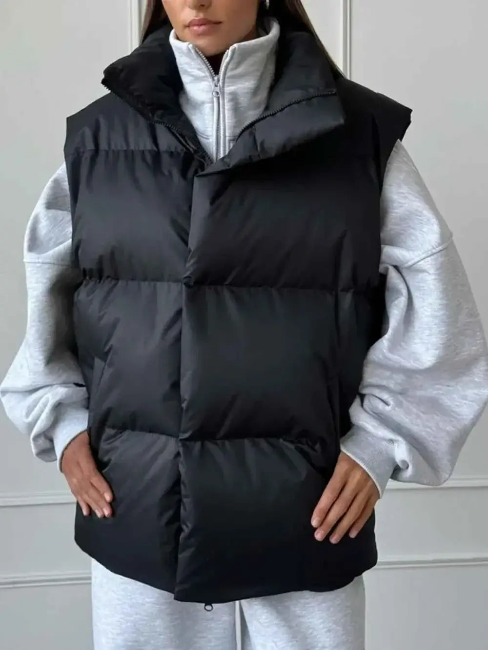 Black quilted Zip Up Turtleneck Vest with padded polyester material and front zipper on model wearing grey sweatshirt