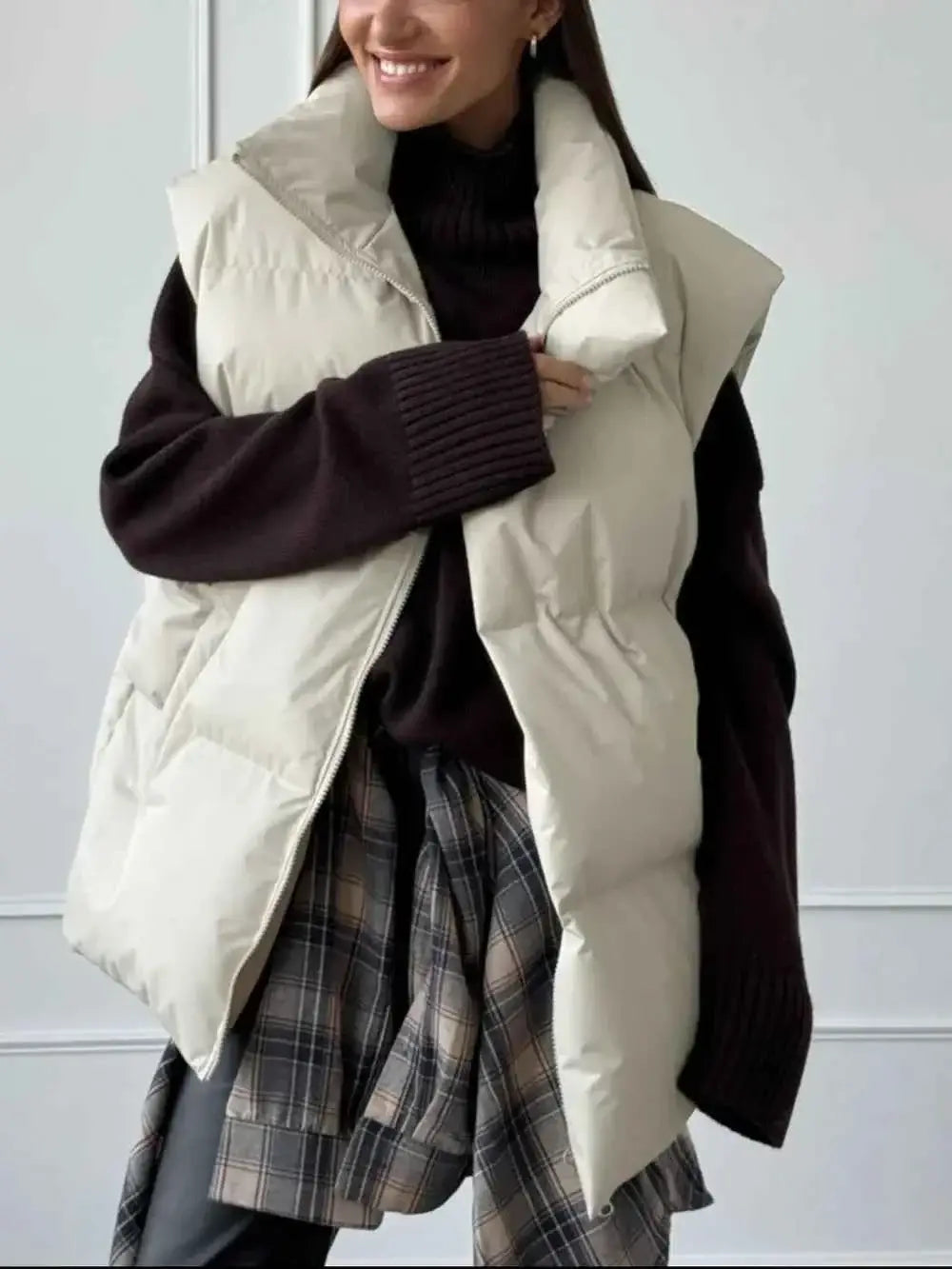 Zip Up Turtleneck Vest in off-white polyester with padded design and front zipper, worn over black knitwear and plaid shirt